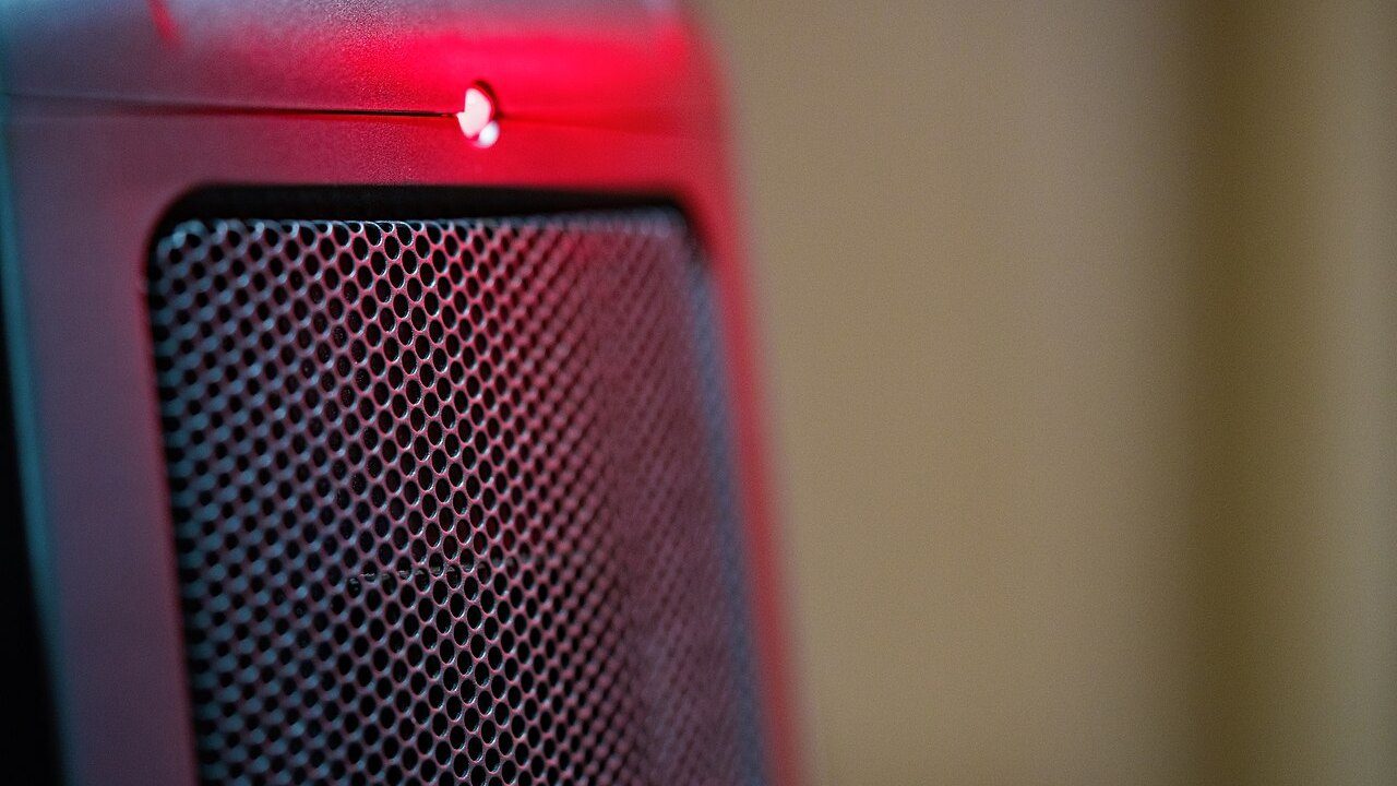 Stufetta elettrica ceramica rossa accesa, con la spia rossa e la griglia in primo piano