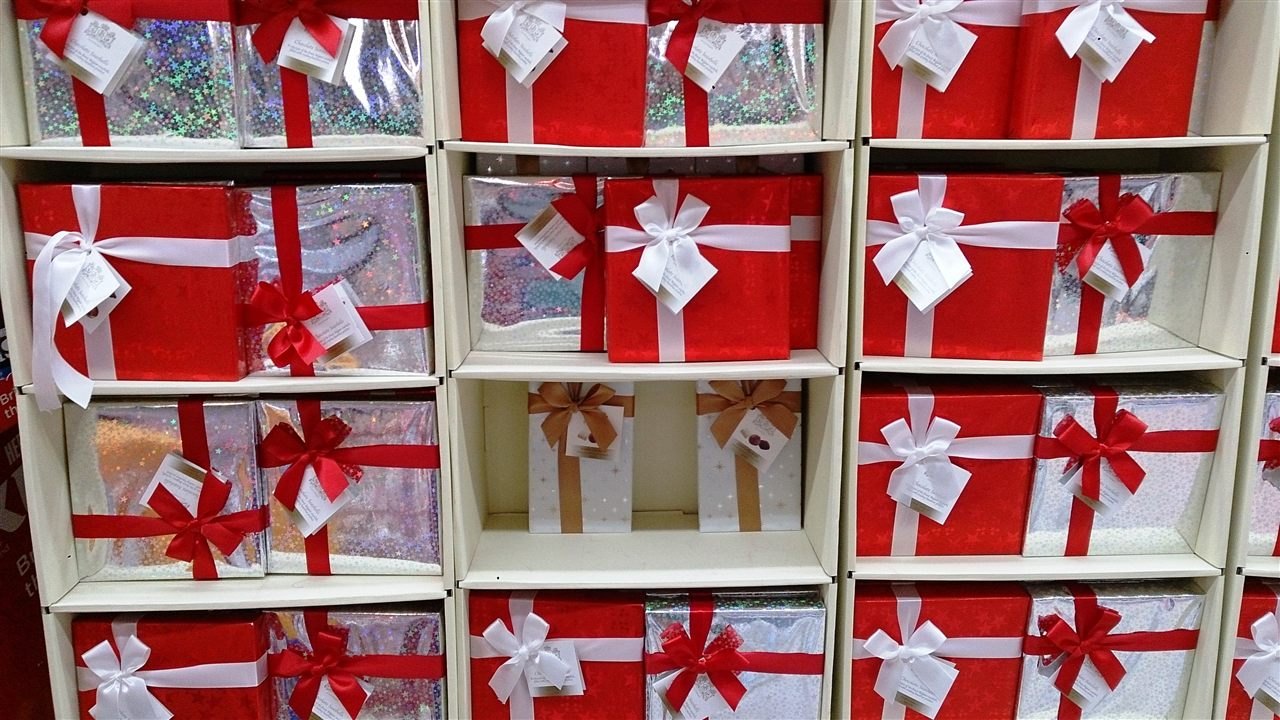 Scaffali pieni di pacchi regalo di Natale rossi e argento con il fiocco e il biglietto