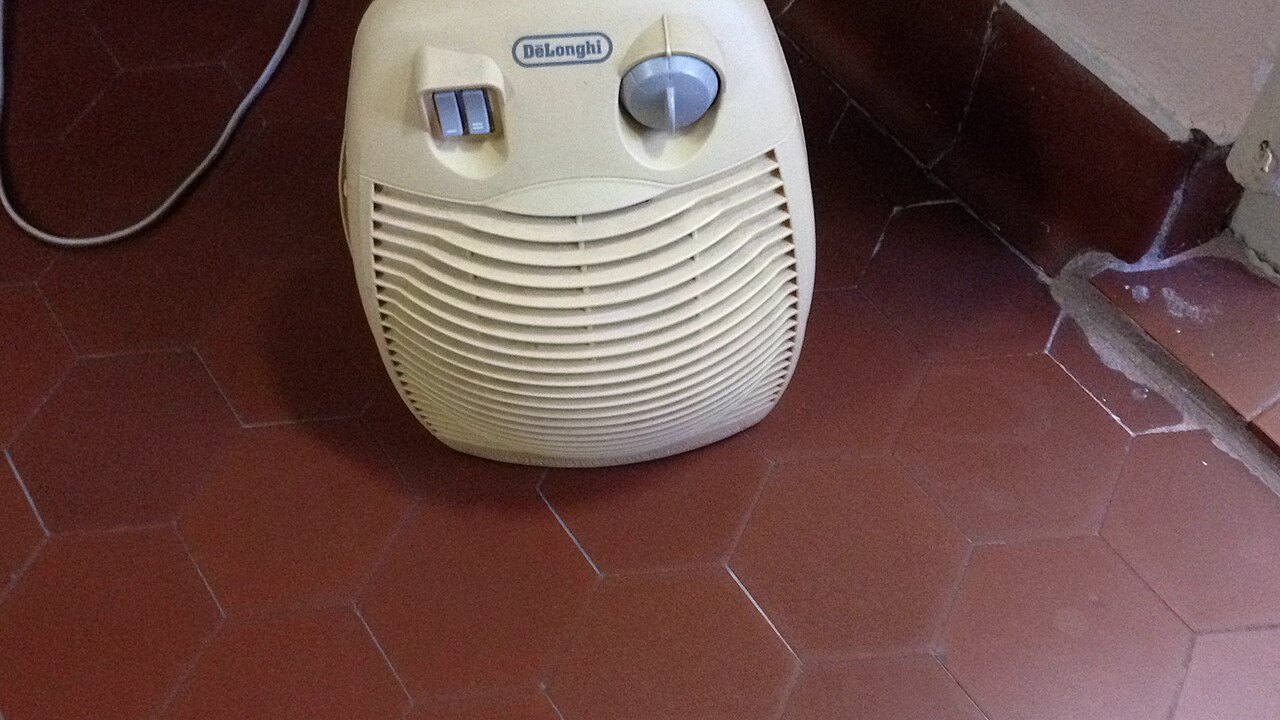 Un termoventilatore De'Longhi appoggiato sul pavimento in cotto di una stanza, con il cavo di alimentazione