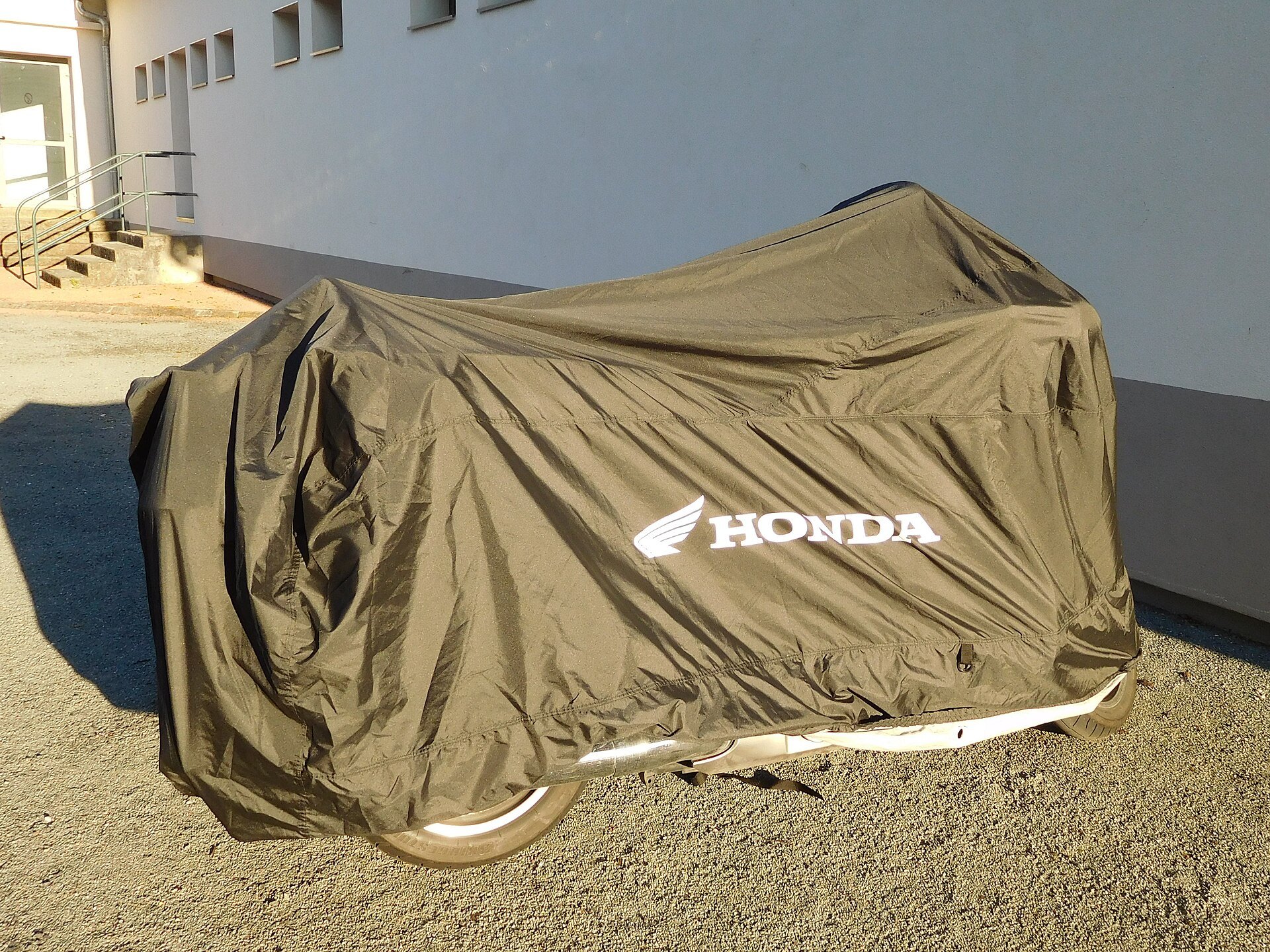 Moto Honda Gold Wing coperta da un telo copri moto grigio in un parcheggio