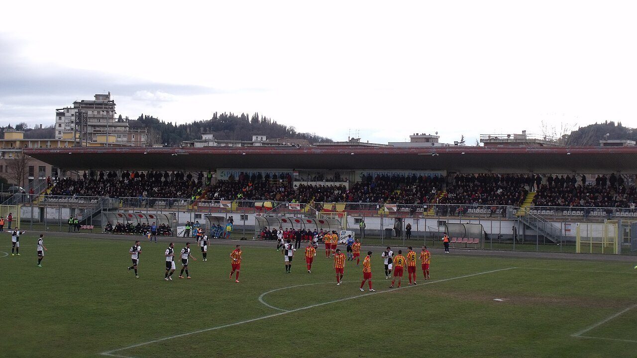 Una partita di Serie D allo stadio Stefano Lotti di Poggibonsi, con la tribuna piena dietro le due squadre in campo