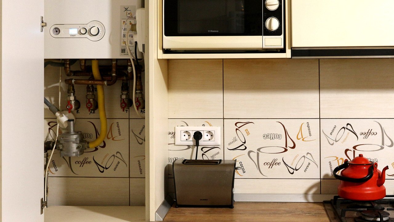 Caldaia murale a gas in un mobile della cucina, con manometro, display e tubi di allacciamento