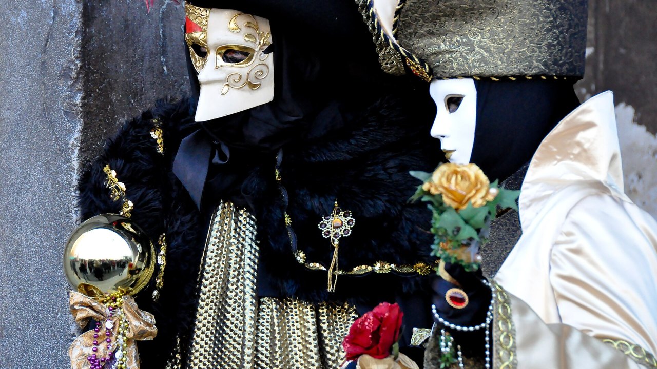 Due maschere veneziane in costume nero e oro al Carnevale di Venezia