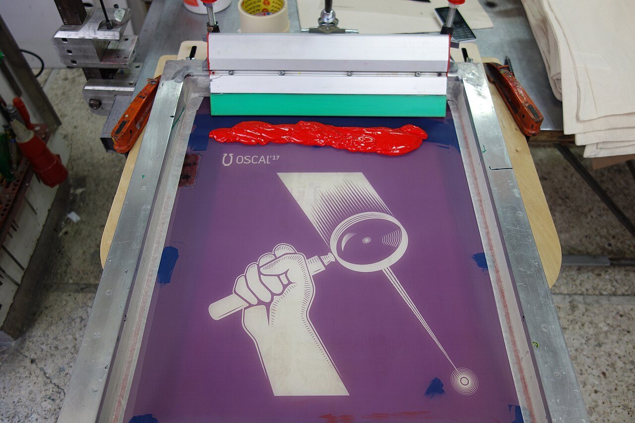 Telaio da serigrafia con la racla e l'inchiostro rosso pronto per la stampa