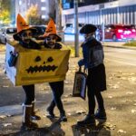 Bambini con costumi di Halloween fai da te: una scatola di cartone dipinta a zucca, cappelli arancioni e trucco sul viso