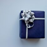 Pacco regalo blu con fiocco argentato su fondo chiaro