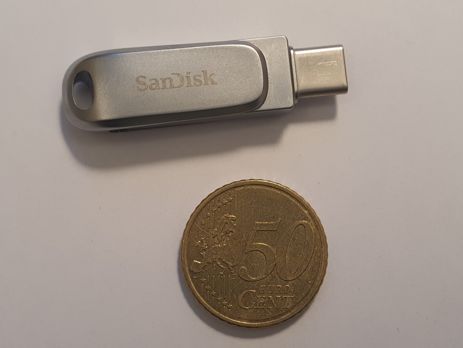 Chiavetta USB SanDisk accanto a una moneta da 50 centesimi