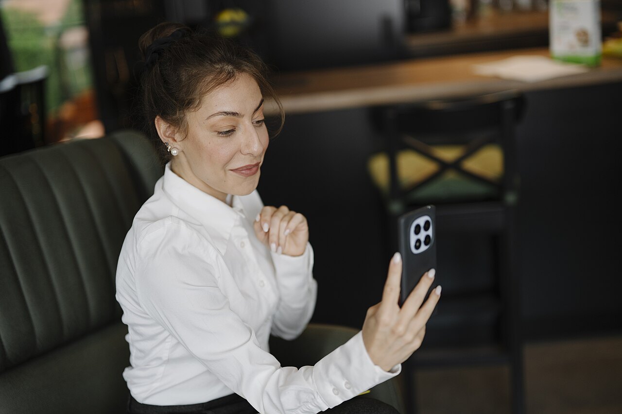 Ragazza seduta in un caffè che fa una videochiamata dal telefono