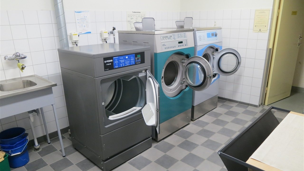 Lavanderia condominiale con asciugatrici e lavatrici a carica frontale in fila