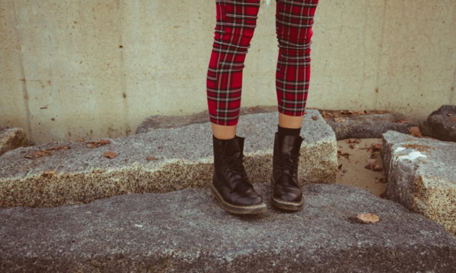 Stivaletti neri in pelle da donna indossati, foglie autunnali sullo sfondo
